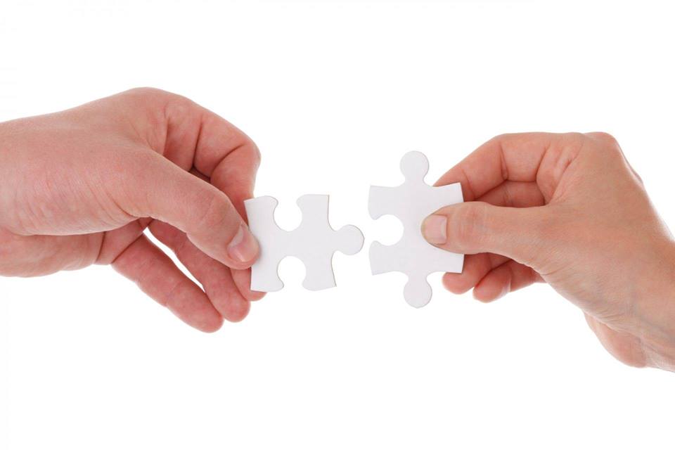 Két kéz két puzzle darabot illeszt össze