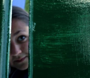 Zöld ajtó mögül néző lány